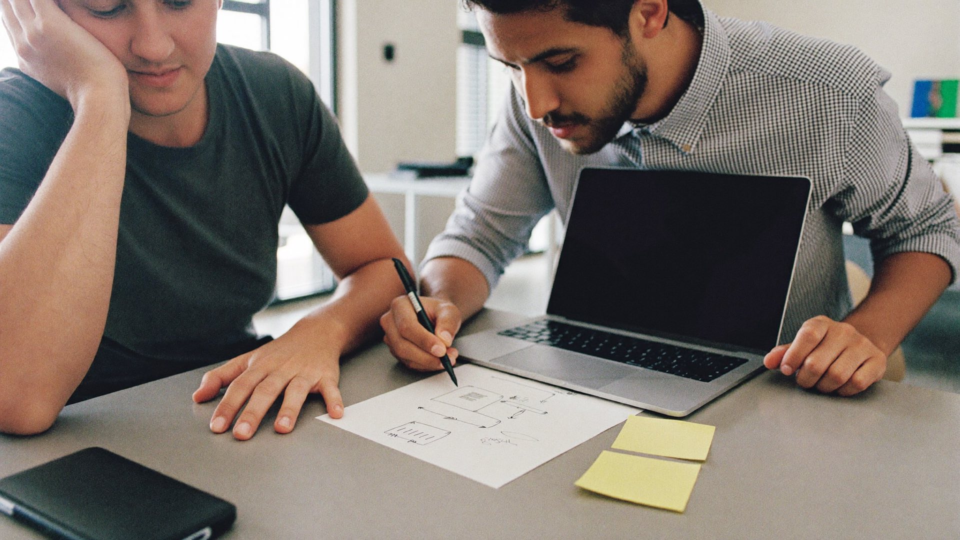 A plain-English chat across a table with a laptop and notes
